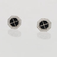 Pair of hexagonal earrings with black centers on a light gray background
