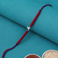 A red braided Rakhi bracelet with a silver-colored swastika symbol charm.