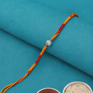 A braided Rakhi bracelet with a silver-colored Om symbol charm.