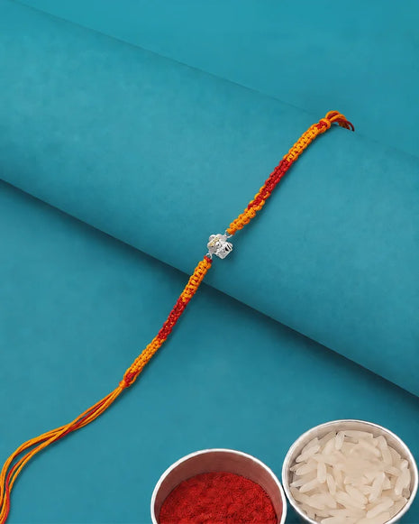 A braided Rakhi bracelet with a silver-colored Om symbol charm.