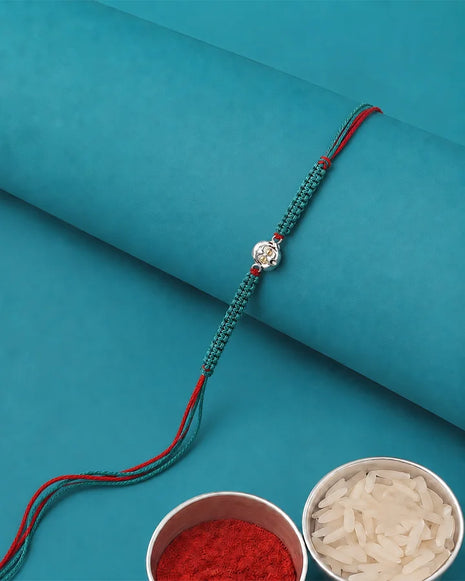 A teal and red braided string bracelet with a silver-toned decorative charm